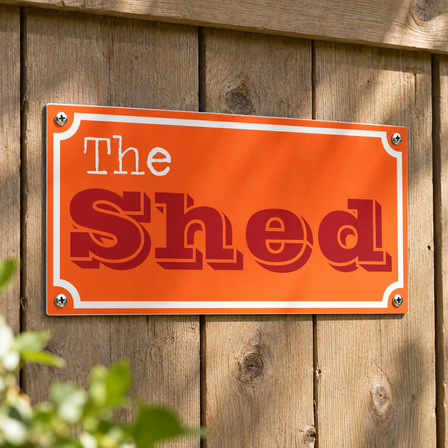 Orange The Shed aluminium sign screwed onto a wooden garden shed