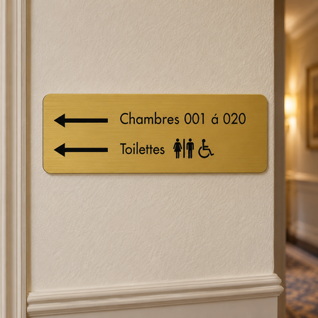 Panneau d'hôtel en plastique gravé doré indiquant les chambres et les toilettes dans un couloir d'hôtel