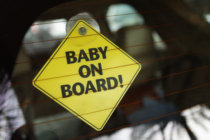 Barn i bilen skylt med texten 'baby on board'