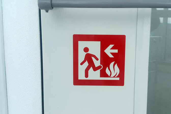 Red emergency sign with a symbol and directional arrow