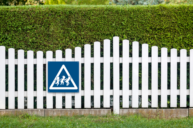Blue and white “Children at Play” sign mounted on a fence